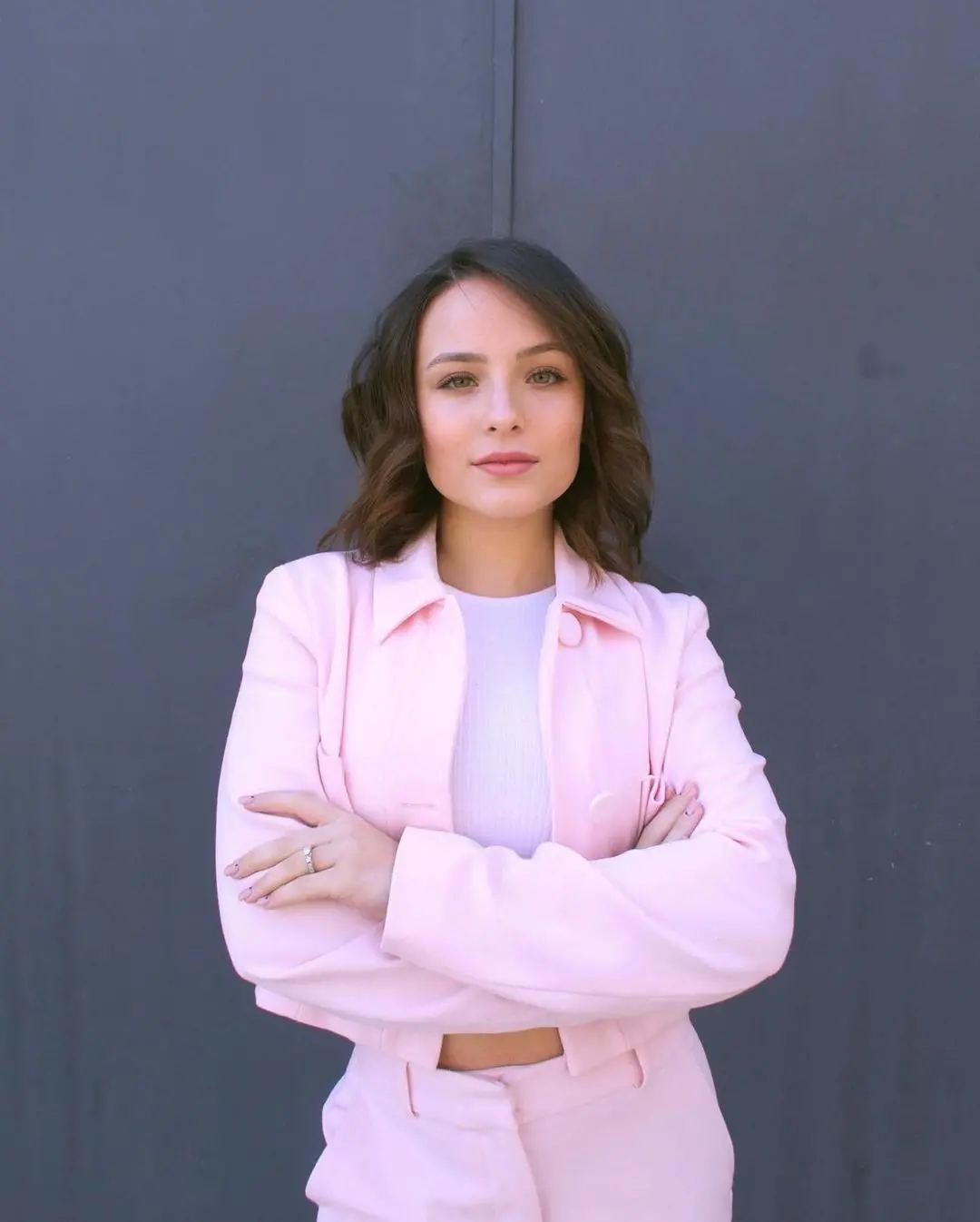 Foto de Larissa Manoela de roupa branca e rosa em parede cinza