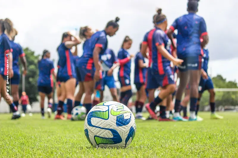 imagem mostra jogadoras de futebol e técnico