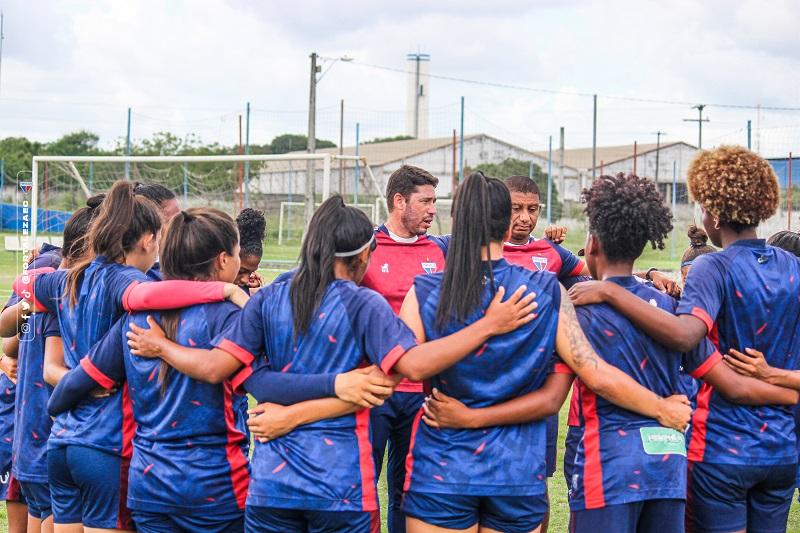 Imagem mostra jogadoras de futebol e técnico