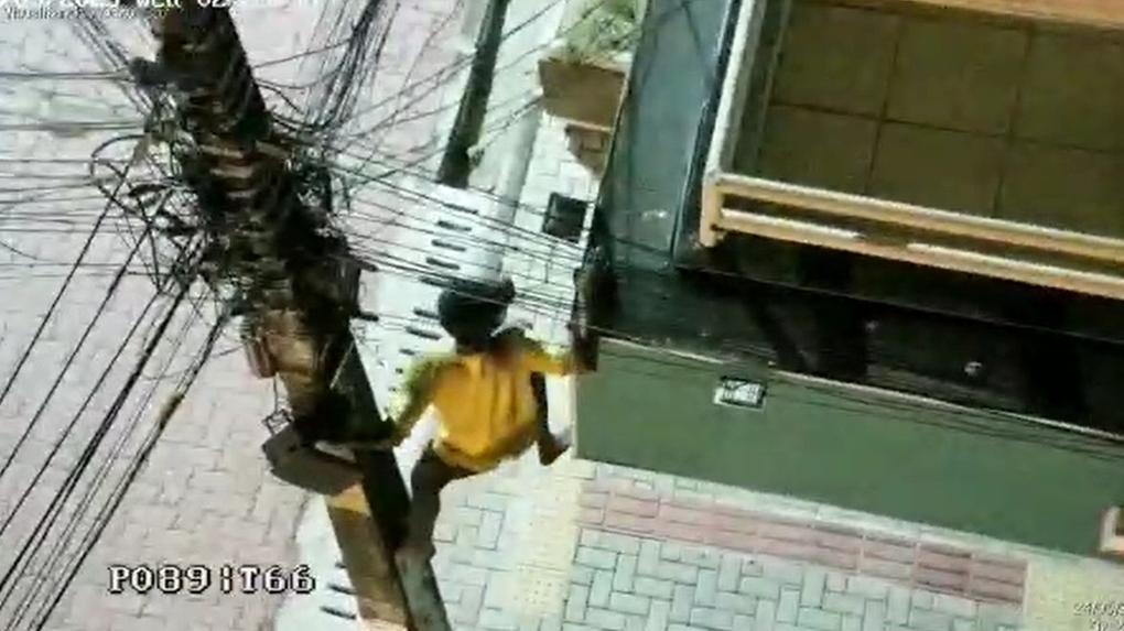 homem escalando poste e subindo muro para furtar fios de cobra