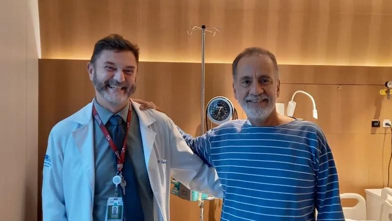 Médico Vanderson Rocha e o paciente Paulo Peregrino abraçados e sorrindo em quarto de hospital