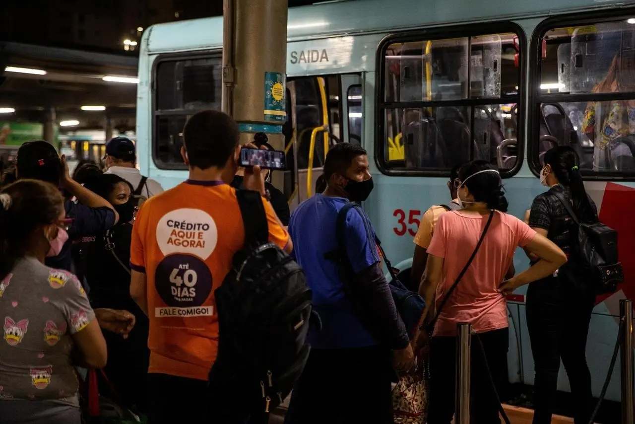 Passageiros aguardam para entrar em ônibus