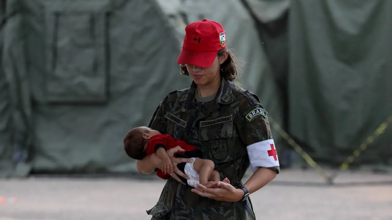 Enfermeira em hospital de campanha carrega criança Yanomami doente
