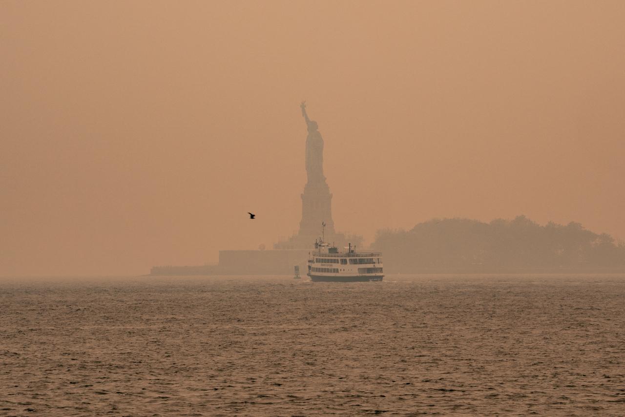 Uma névoa esfumaçada de incêndios florestais no Canadá envolve a Estátua da Liberdade em Upper Bay em 7 de junho de 2023 na cidade de Nova York.