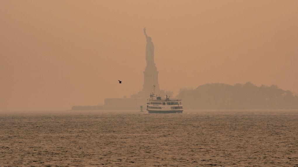 Uma névoa esfumaçada de incêndios florestais no Canadá envolve a Estátua da Liberdade em Upper Bay em 7 de junho de 2023 na cidade de Nova York.