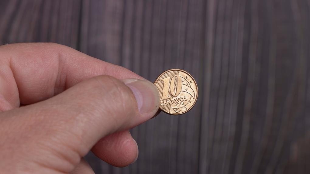Mão segurando moeda de 10 centavos