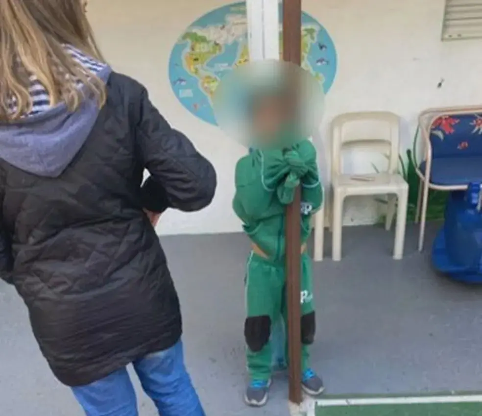 Menino amarrado pela blusa a um poste