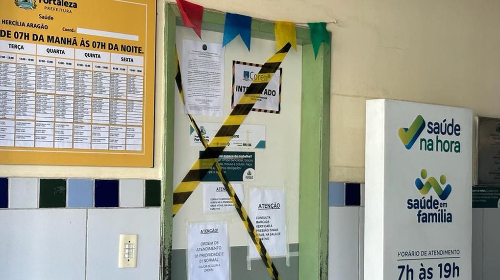 Imagem mostra porta de sala do Posto de Saúde Irmã Hercília Aragão com fitas indicando interdição pelo Coren em 27 de junho de 2023