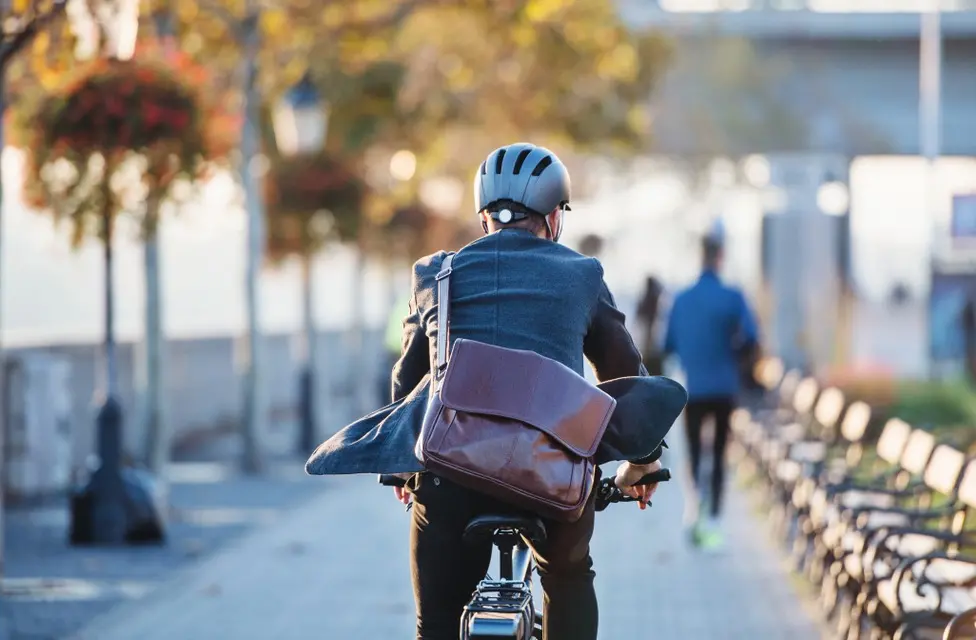 Ciclista de terno usa bicicleta elétrica em parque