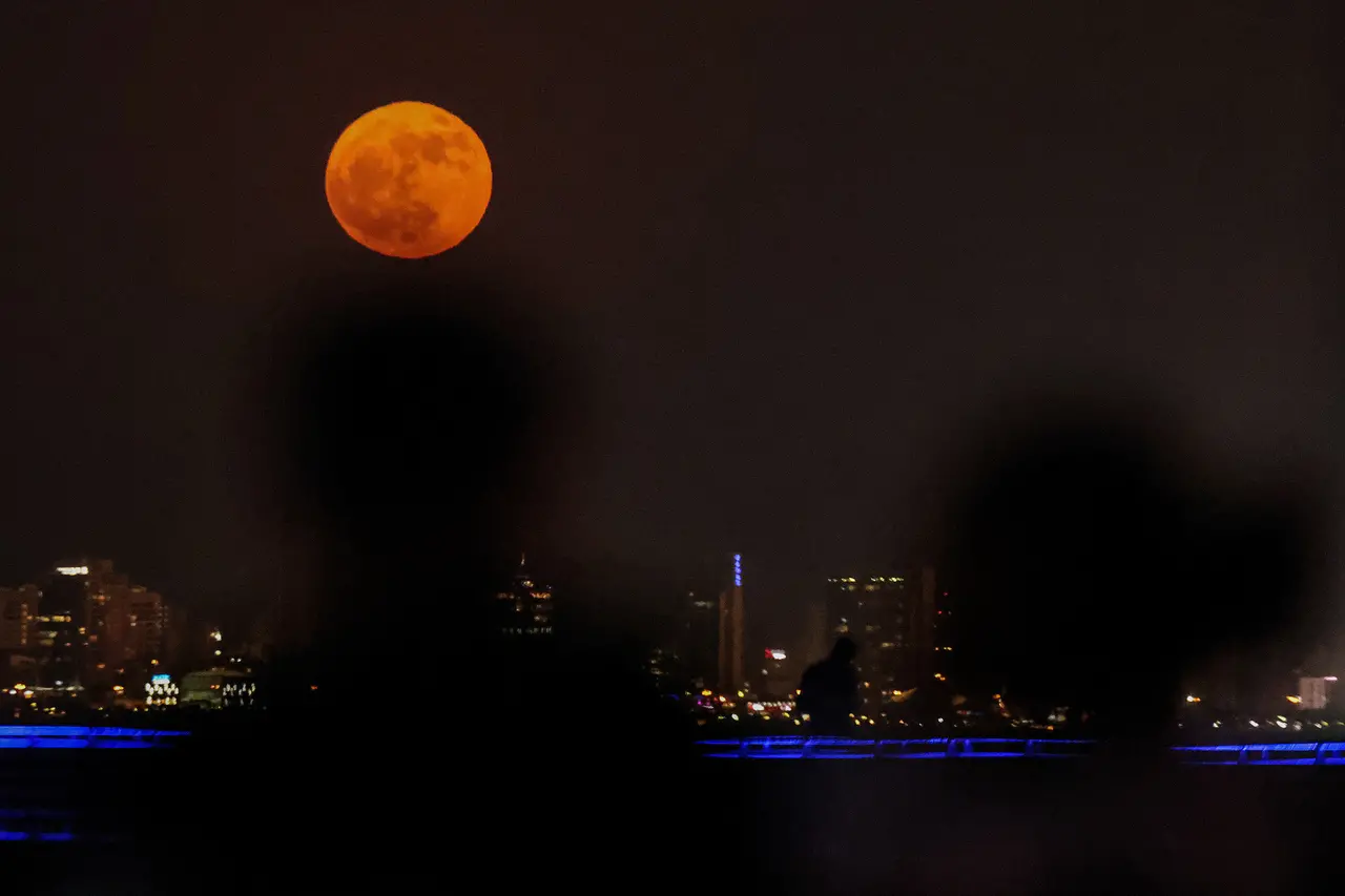 Pessoas observam a 'Superlua dos Cervos' surgir no horizonte da cidade do Kuwait em 3 de julho de 2023.