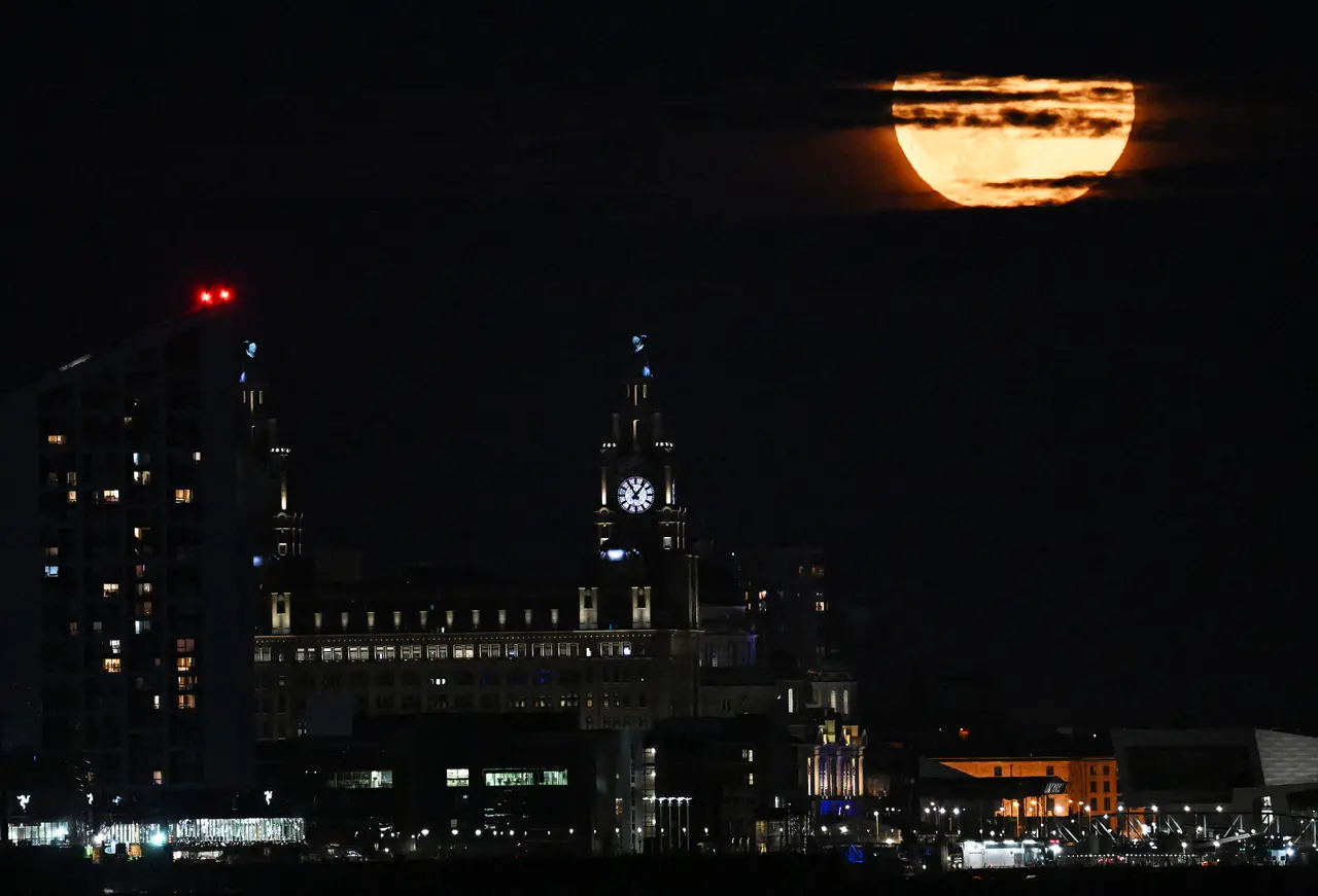 'Superlua dos Cervos' surge entre as nuvens atrás do Edifício Liver em Liverpool, noroeste da Inglaterra, no final de 3 de julho de 2023.