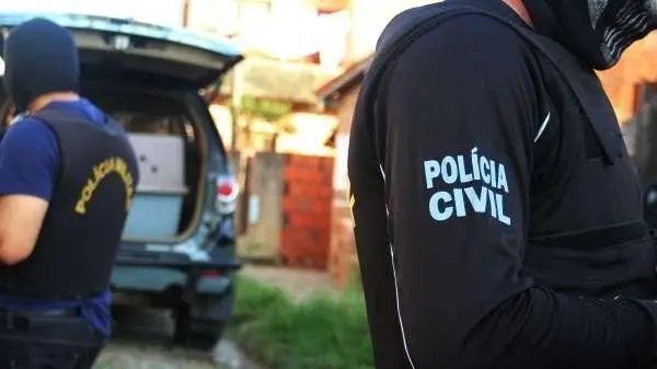 Policiais não identificados estão em frente a uma viatura