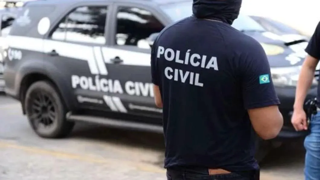Policial civil de costas em frente a uma viatura