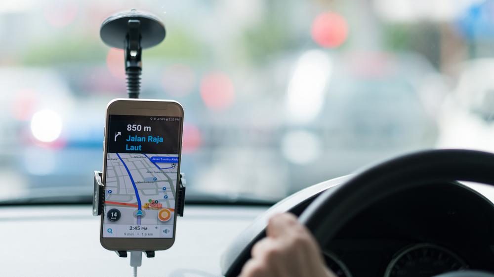 Motorista por aplicativo dirige enquanto olha mapa pelo celular