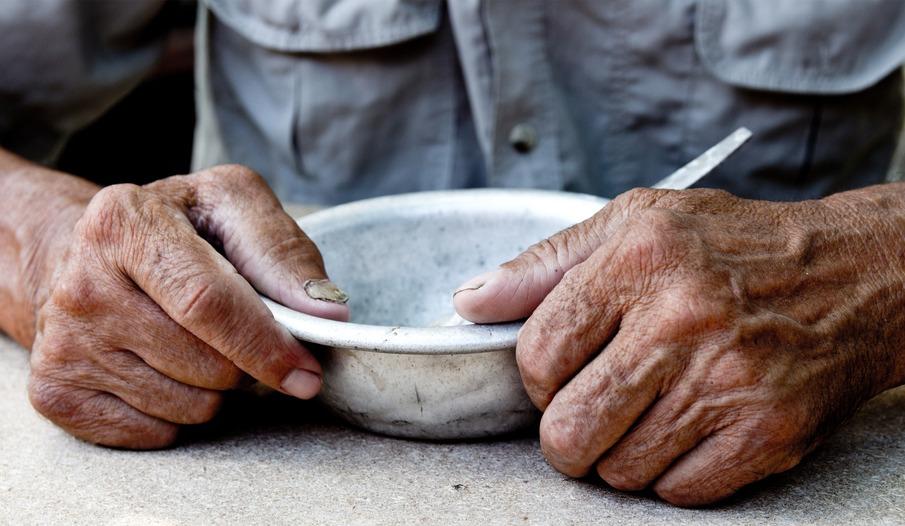 Mão de idoso segura prato de inox vazio
