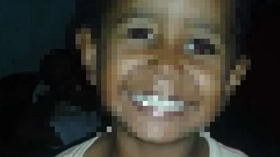 Otiniel é um menino negro, de seis anos de idade. Na foto, ele está sorrindo e olhando para cima