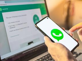 Mão segura celular aberto no WhatsApp