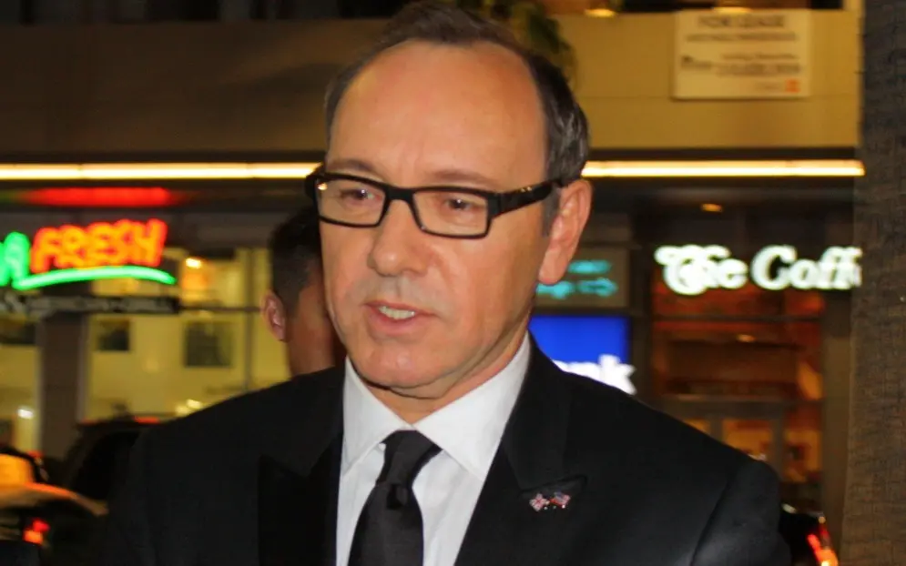 Kevin Spacey é um homem branco, de meia idade, que usa óculos de armação grossa preta