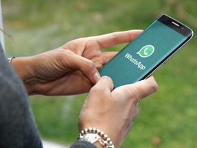 Mão segurando celular aberto no WhatsApp