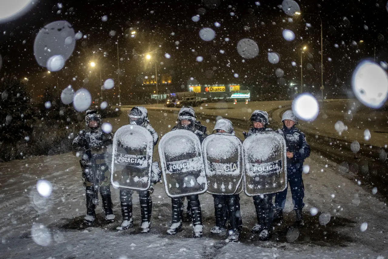 Policiais protegem um supermercado Diarco (parte traseira) sob neve que cai após uma tentativa de saque, em Bariloche, província de Rio Negro, Argentina, em 23 de agosto de 2023.