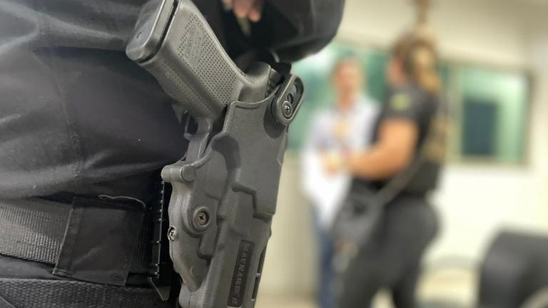 Imagem mostra foco em arma guardada em porta-arma atada a perna de policial federal