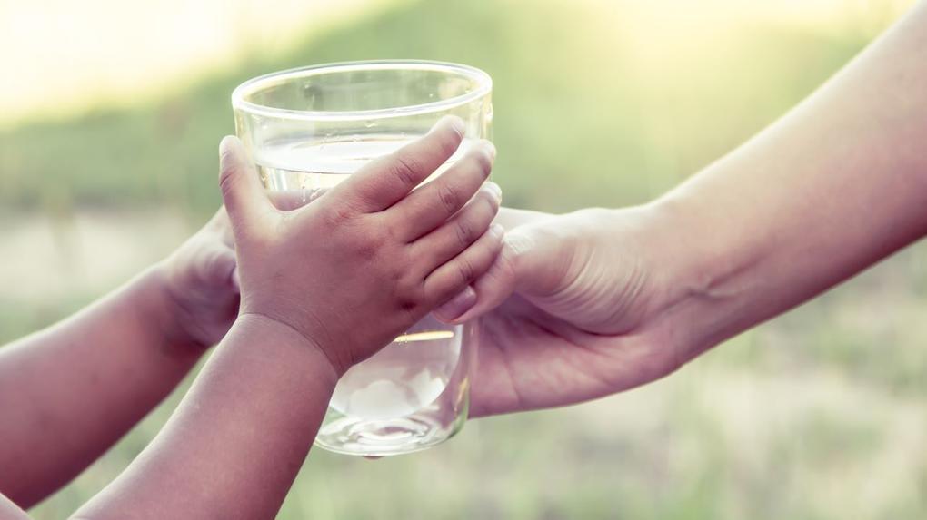 criança recebendo copo d'água