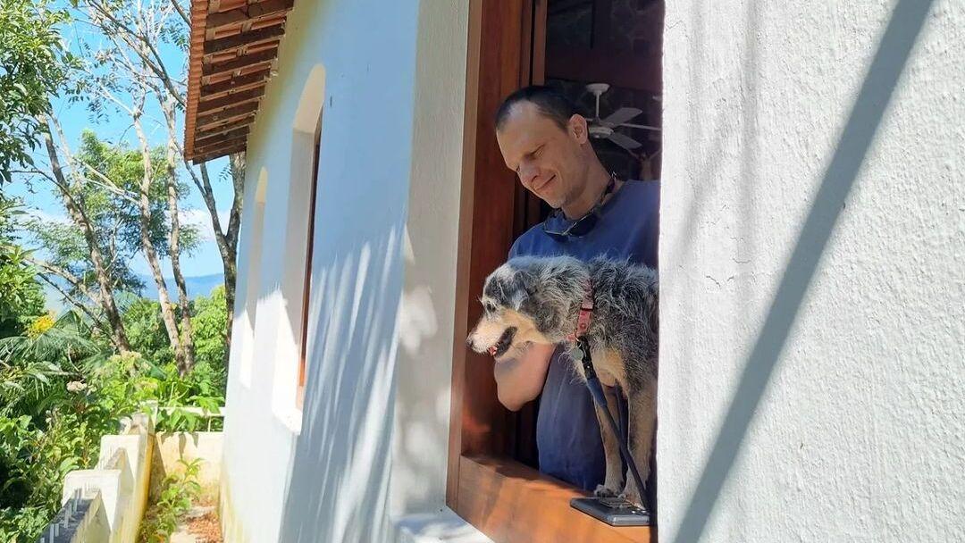 Alexandre Rossi e Estopinha na janela de uma casa