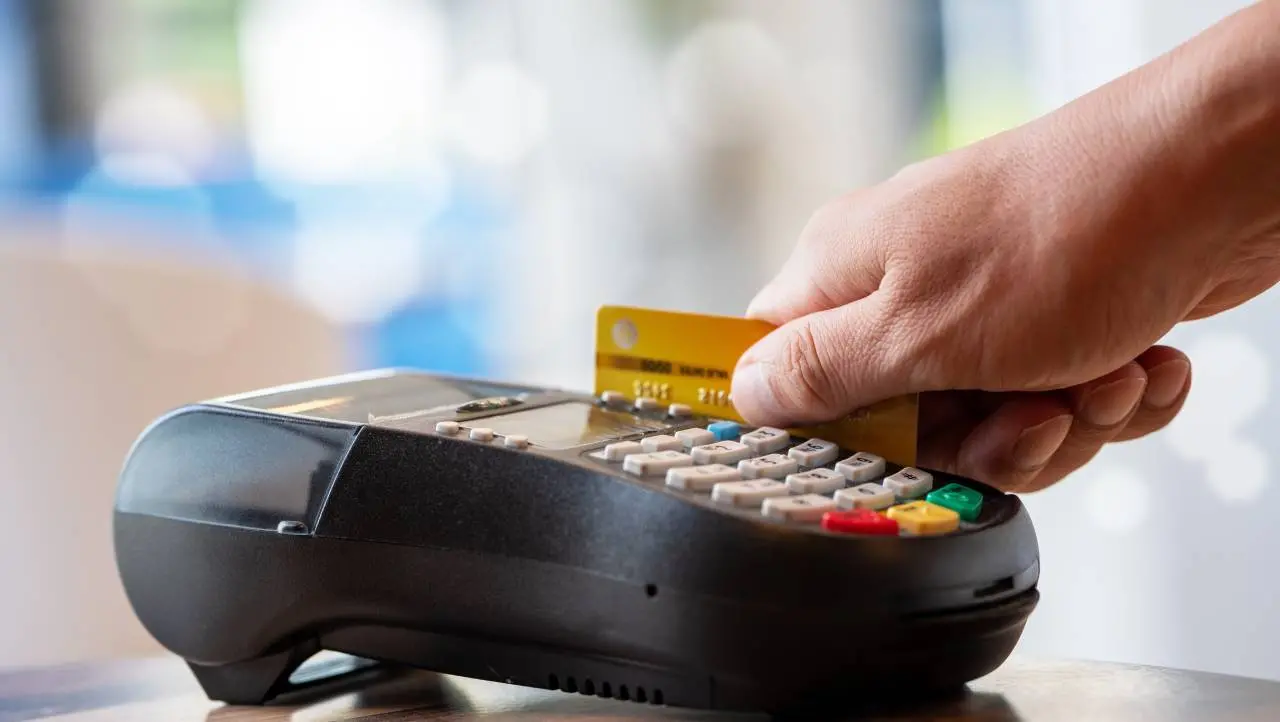 Mão passando cartão de crédito em maquineta