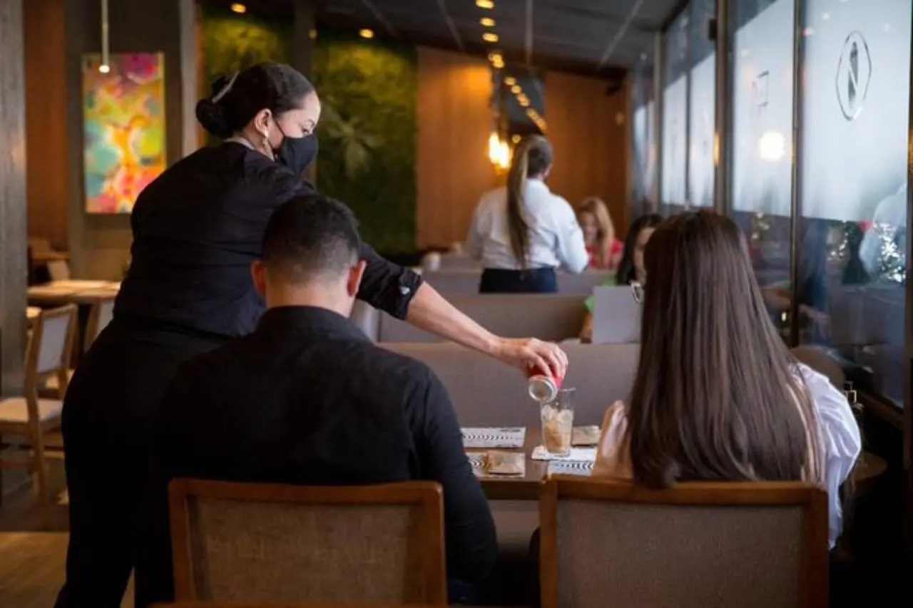 Casal de costas em restaurante sendo servido por garçonete