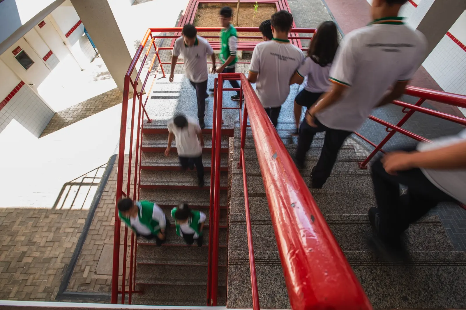 Estudantes descendo para o pátio da escola