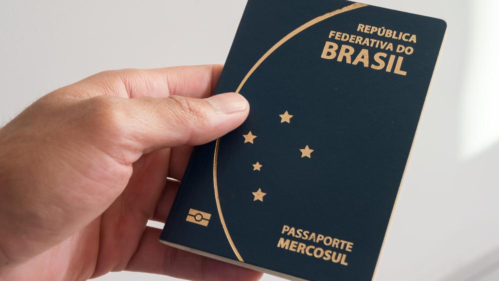 Mão segurando passaporte brasileiro