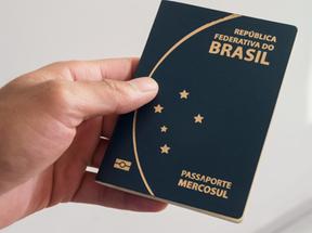 Mão segurando passaporte brasileiro