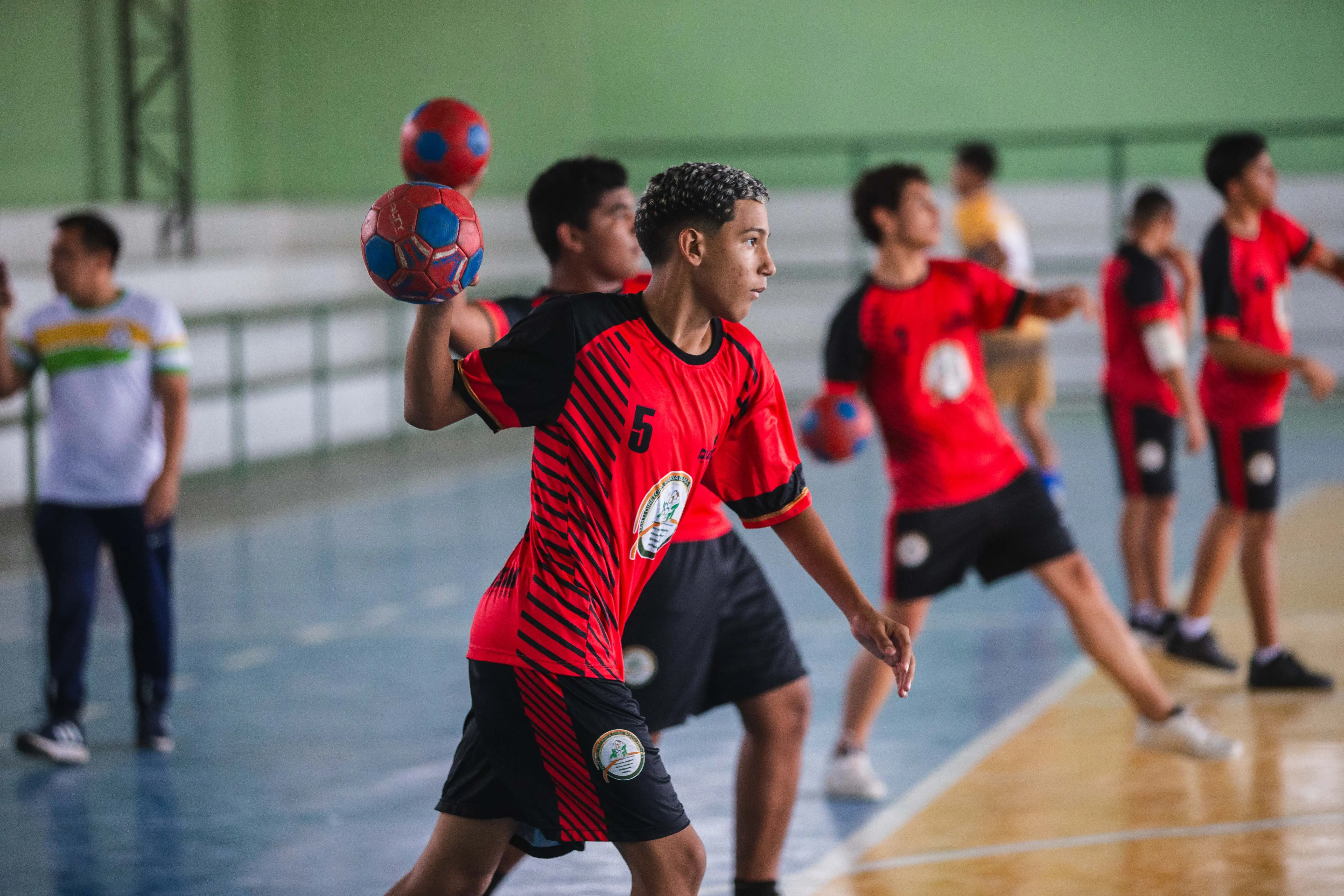 Alunos jogando handball em quadra esportiva
