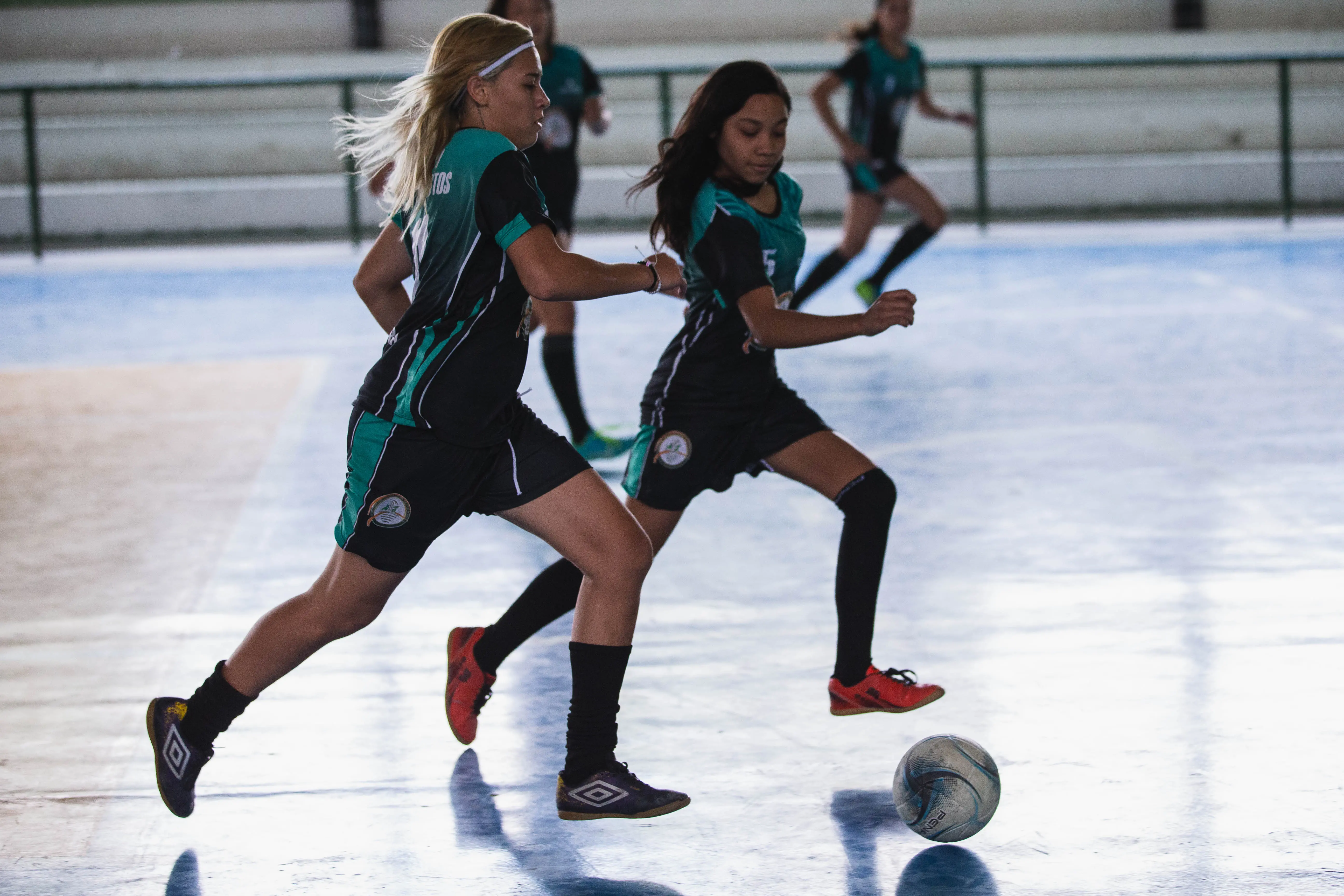 Alunas jogando futebol em quadra esportiva