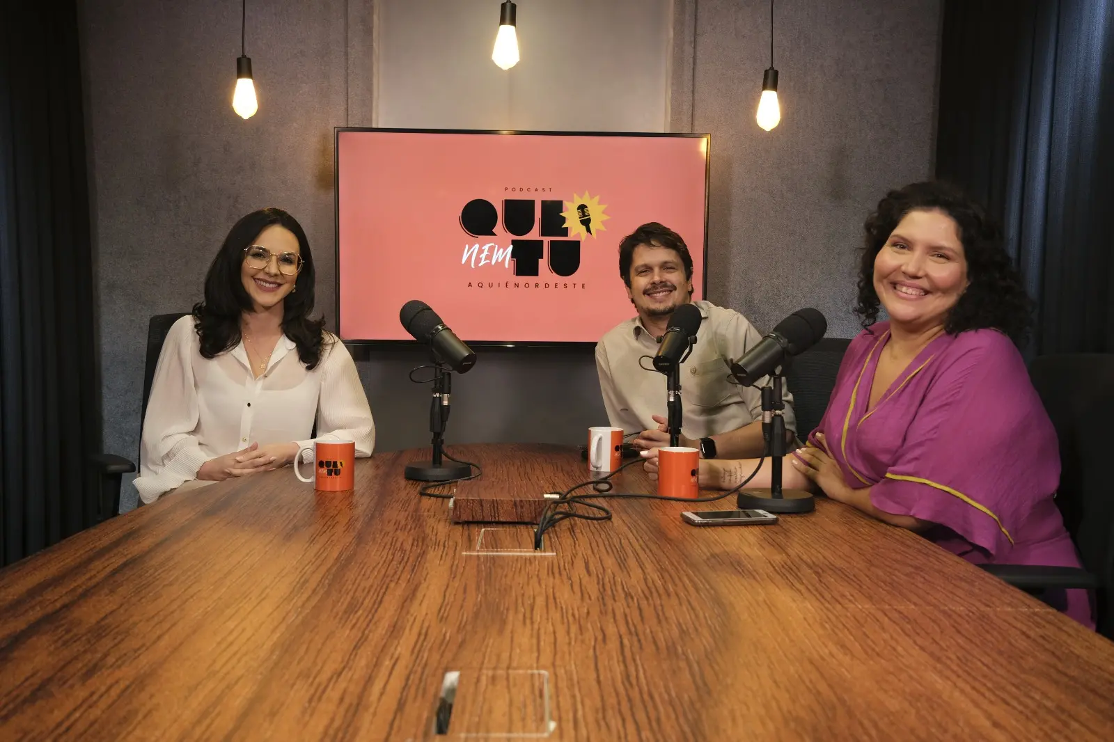 A psicóloga Maria Camila Moura sentada à mesa de podcast com os os jornalistas Alan Barros e Karine Zaranza