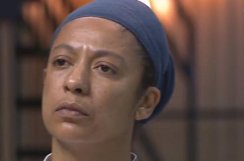 Cíntia Sanchez está usando uma touca preta e com a expressão séria