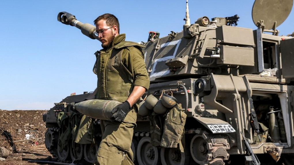 Um soldado do exército israelense reage enquanto transportava um projétil de artilharia de 155 mm perto de um obus autopropulsado posicionado em uma posição perto da fronteira com o Líbano, na região da alta Galiléia, no norte de Israel, em 18 de outubro de 2023. Israel diz ter matado líder de braço militar de grupo radical na Faixa de Gaza