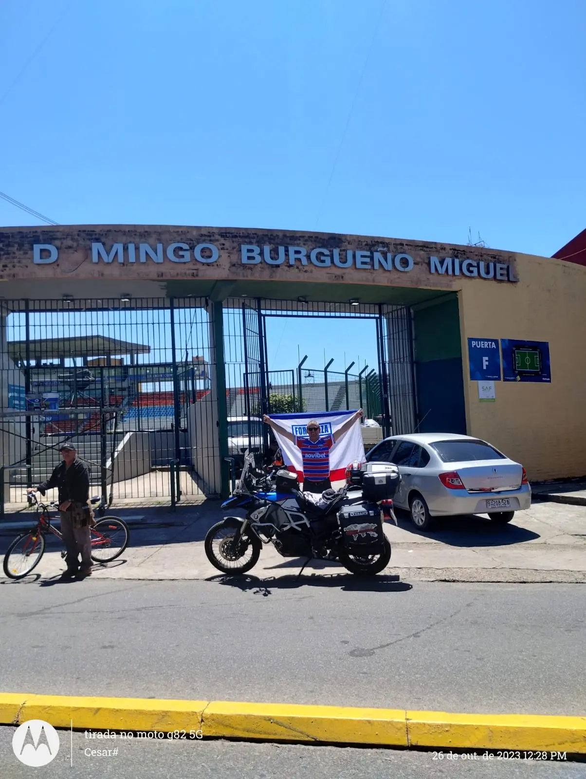 Imagem mostra motociclista em frente a estádio de futebol
