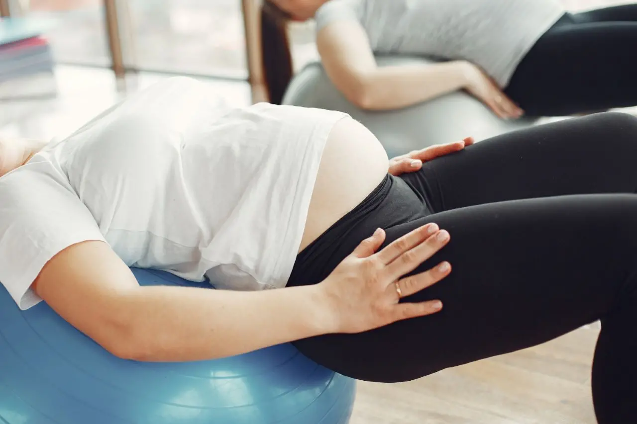 gestante fazendo alongamento sobre bola de pilates