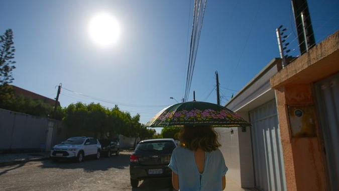 Mulher segurando guarda-chuva para se proteger do sol