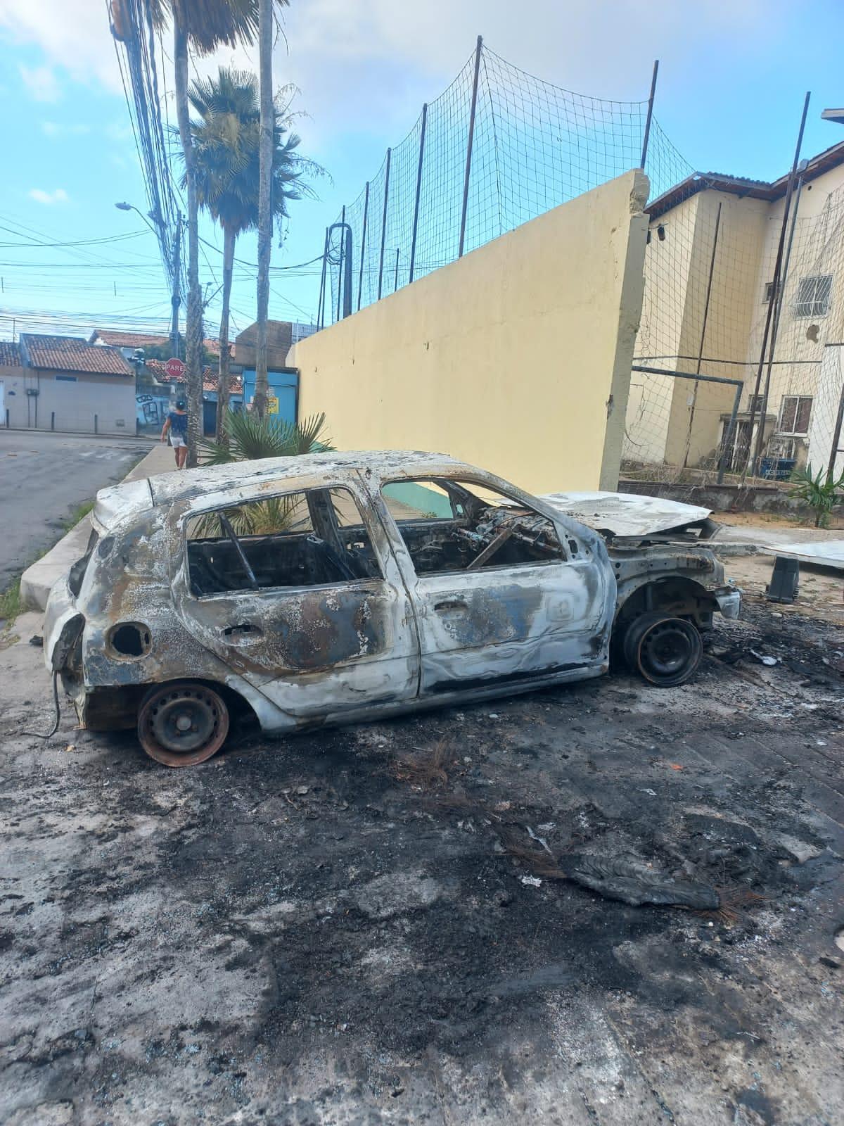 Criminosos efetuaram vários disparos em um portão de um condomínio e depois arremessaram um veículo contra o mesmo portão. O carro, depois, foi incendiado