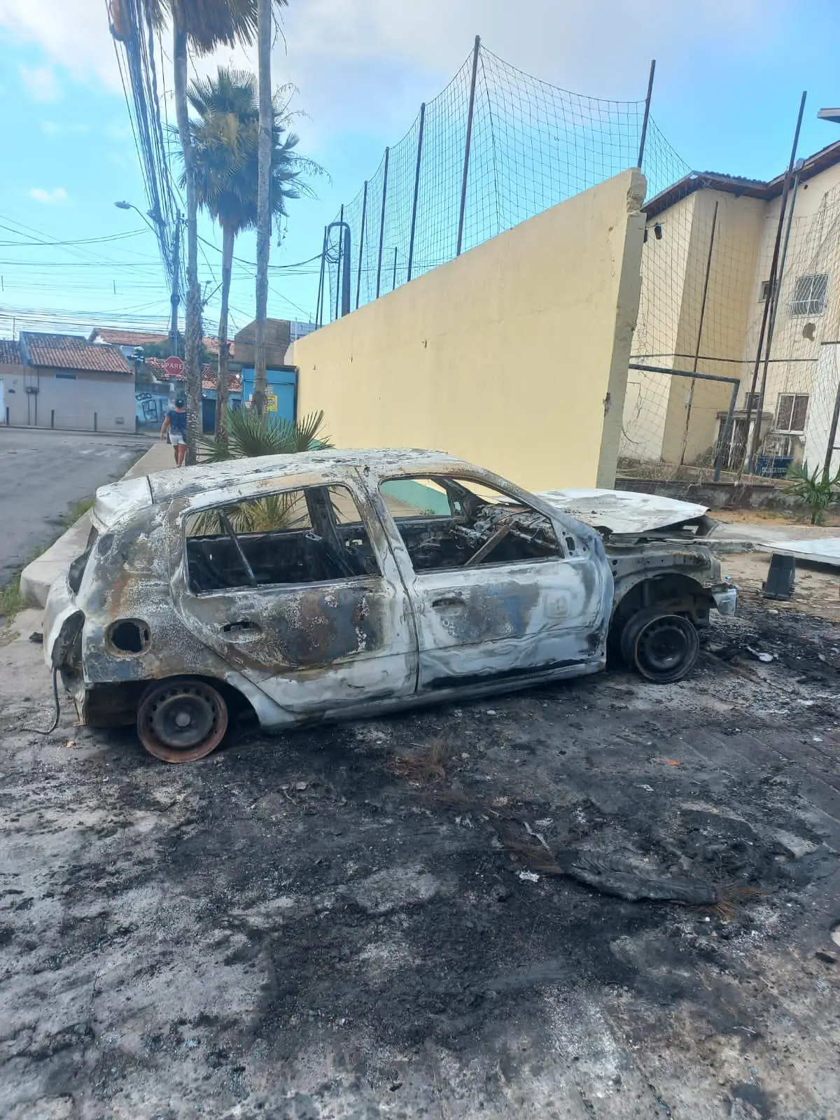 Criminosos efetuaram vários disparos em um portão de um condomínio e depois arremessaram um veículo contra o mesmo portão. O carro, depois, foi incendiado