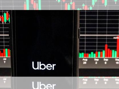 Celular com a logo da Uber em frente a uma tela de computador com gráficos em barra