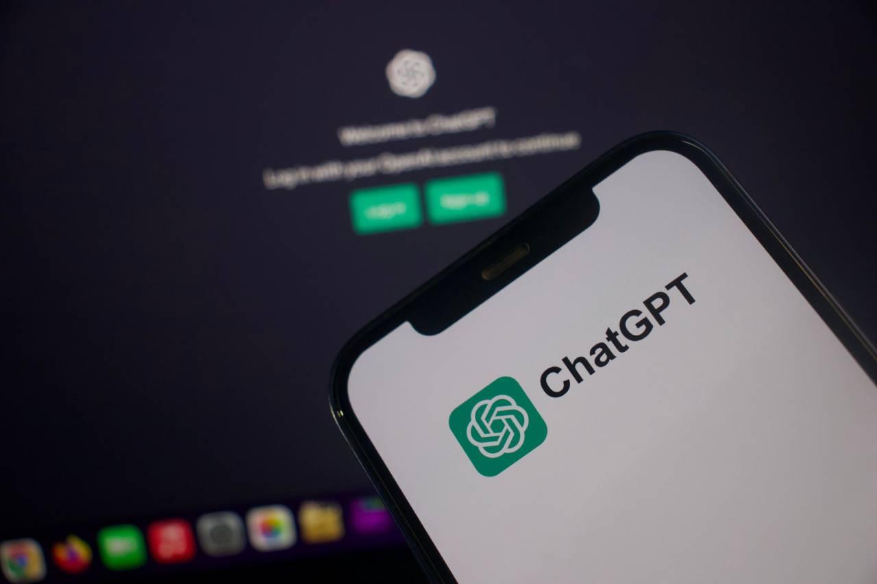 Celular em frente a computador, com ambas as telas mostrando o ChatGPT.