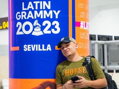 João Gomes ao lado de cartaz do grammy latino