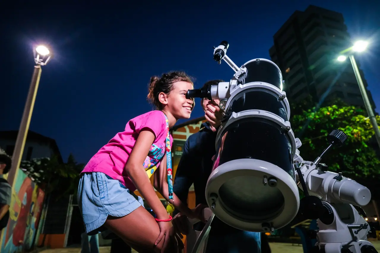 foto de criança observando o céu de Fortaleza com auxílio de um telescópio.