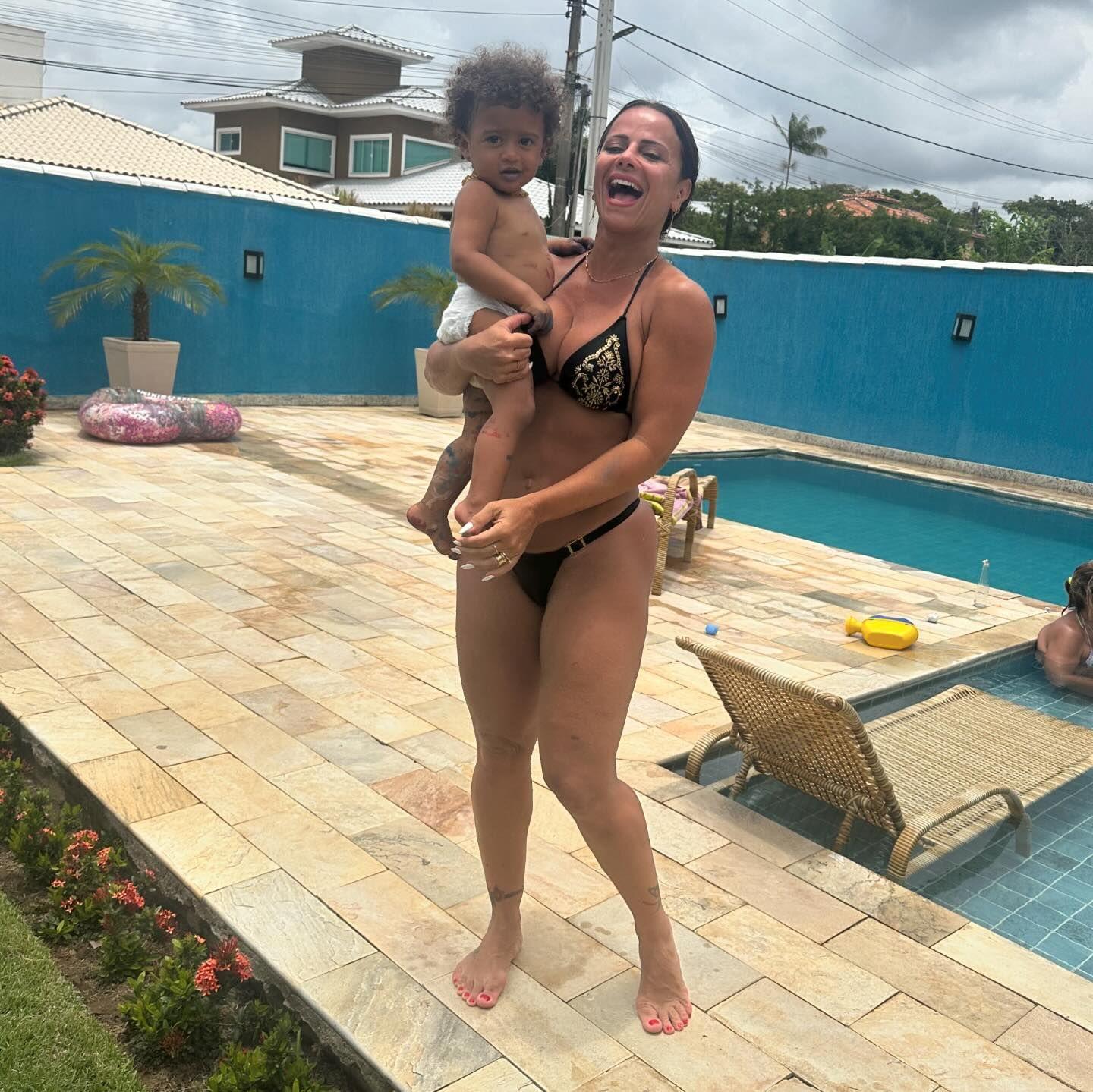 A atriz Viviane Araújo posa em frente à piscina com o filho Joaquim nos braços