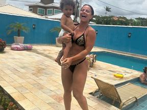 A atriz Viviane Araújo posa em frente à piscina com o filho Joaquim nos braços