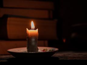 A luz de velas ilumina o quarto escuro de uma casa rural onde estão os livros sobre uma mesa rústica de madeira. Conceito de educação em zonas rurais que não têm acesso a eletricidade para iluminação. Moradores denunciam instabilidade e falta de energia elétrica em diversas cidades no Ceará