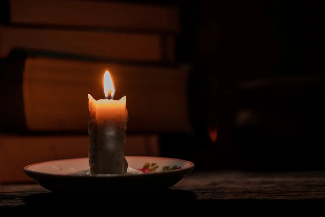 A luz de velas ilumina o quarto escuro de uma casa rural onde estão os livros sobre uma mesa rústica de madeira. Conceito de educação em zonas rurais que não têm acesso a eletricidade para iluminação. Moradores denunciam instabilidade e falta de energia elétrica em diversas cidades no Ceará